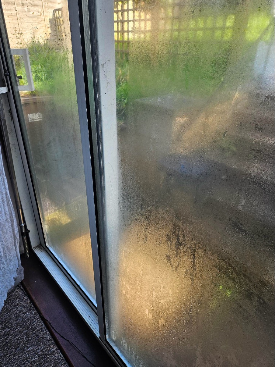 Heavy condensation covering a patio door, obscuring the view into the garden