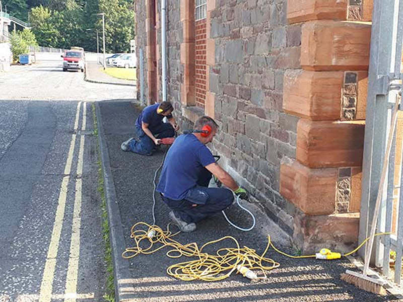 Technicians carrying out damp-proof course injection as part of damp bridging remedial work