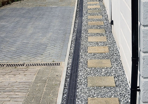Gravel drainage margin and channel drain installed alongside a property wall to correct damp bridging